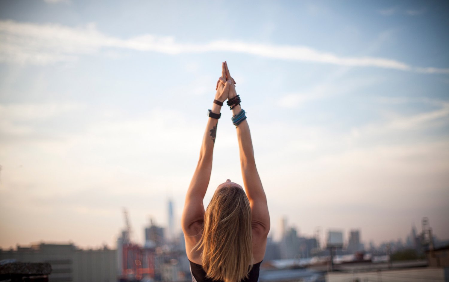 A student in a rooftop sun salutation with the Manhattan skyline behind her